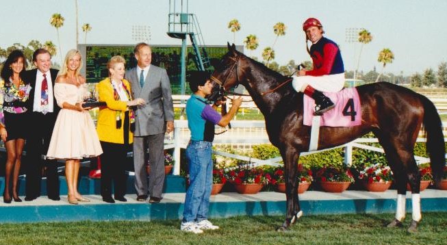 Irv Cowan (dark suit) and Marjorie Cowan (gold jacket) celebrate the Hollywood Oaks with their filly. (Photo by Stidham & Assoc., courtesy of Hollywood Park, provided by Edward Kip Hannan & Roberta Weiser)